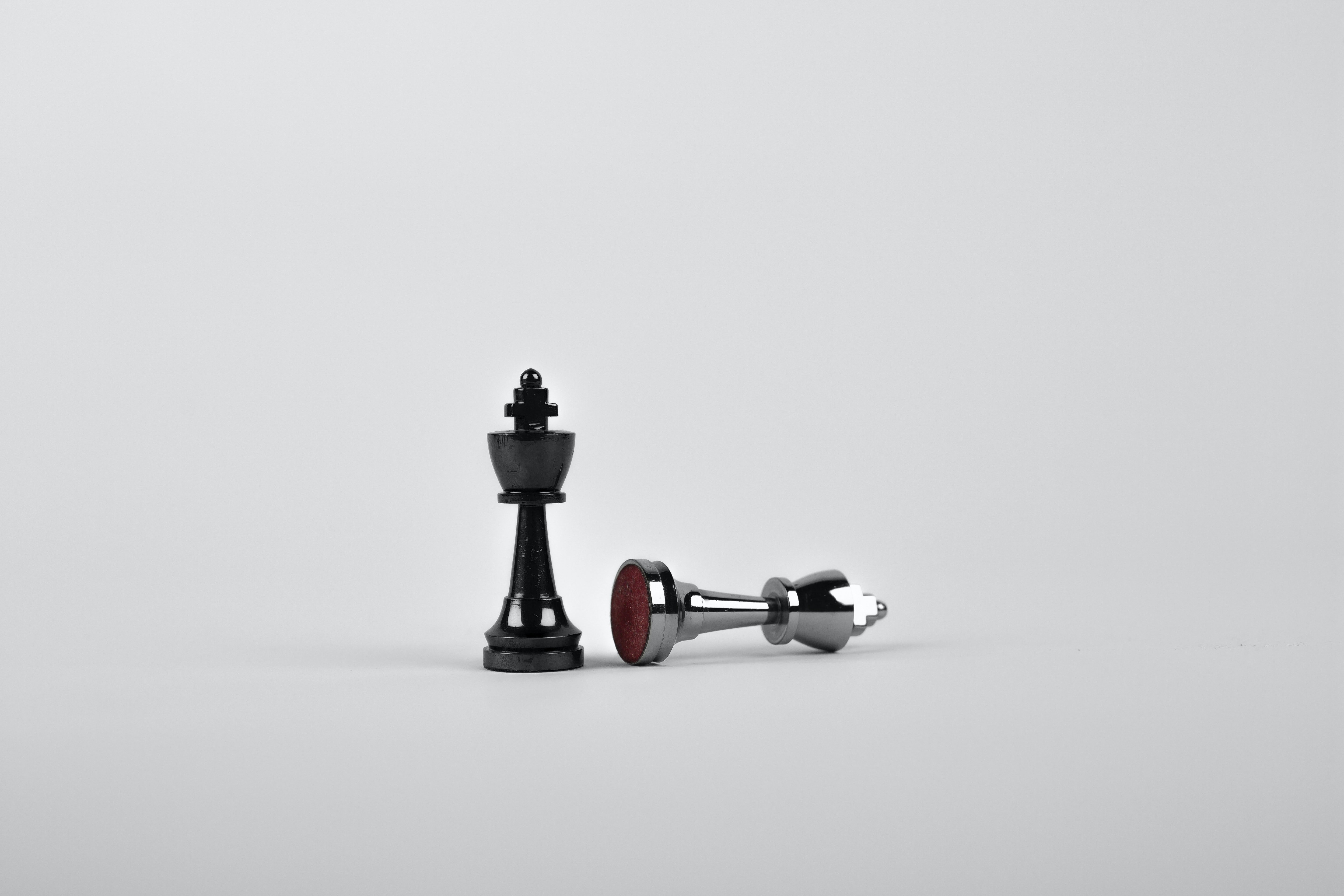 a white chess king fallen next to a black chess king